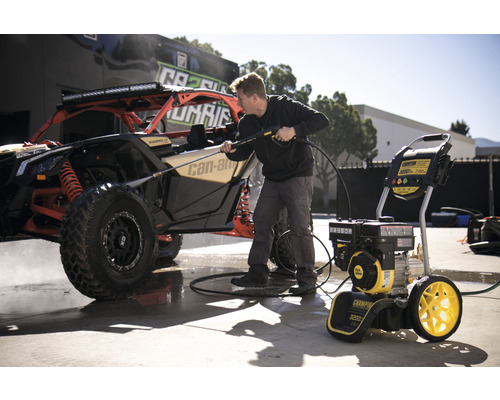 Eine Person reinigt ein Geländefahrzeug mit einem Hochdruckreiniger.
