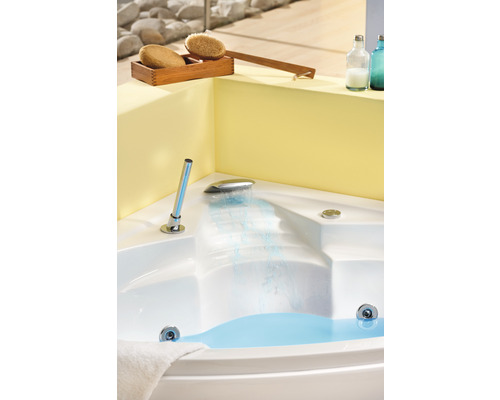 Eckbadewanne mit Wasser, Armatur und Wellness-Zubehör im Badezimmer