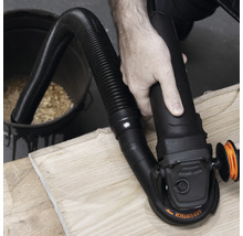 Eine Person schleift ein Holzstück mit einem Schleifgerät mit Staubabsaugung.