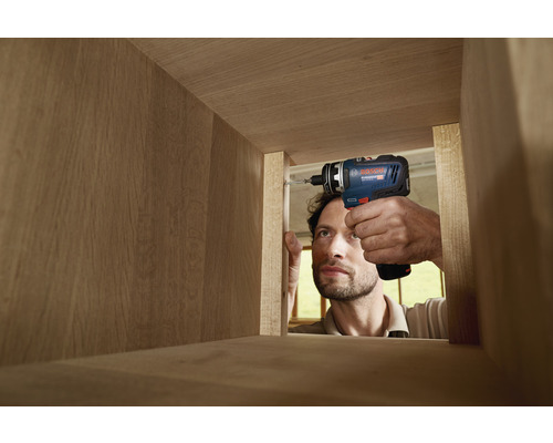 Handwerker schraubt Schraube mit Akku-Bohrschrauber in Holzkonstruktion