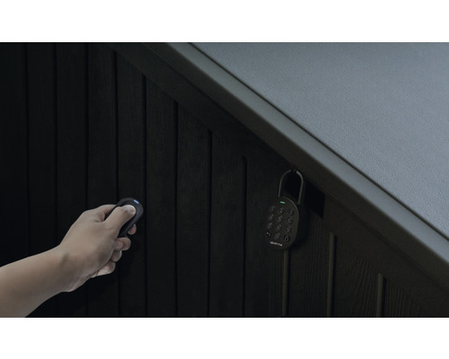 Hand mit Fernbedienung und Zahlenschloss