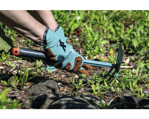 Person entfernt Unkraut mit einer Gartenhacke und trägt dabei Gartenhandschuhe.