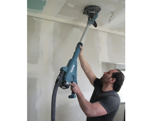 Mann verwendet einen Trockenbauschleifer von Makita an einer Decke