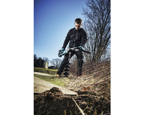 Ein Mann benutzt einen Erdbohrer im Garten.
