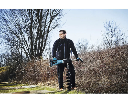 Ein Mann steht im Freien und hält einen Erdbohrer.