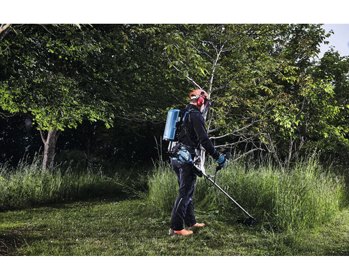 Person bedient Rasentrimmer mit Akku-Rückentragegerät im Garten.