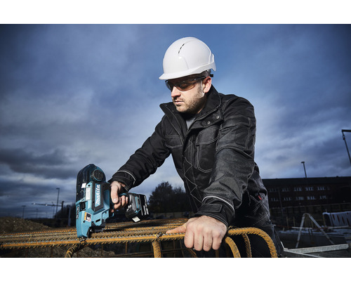 Mann mit Schutzhelm und Schutzbrille bedient einen Akku-Bindedrahtautomaten von Makita auf einer Baustelle zum Verarbeiten von Bewehrungsstahl.
