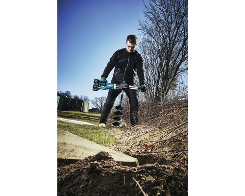 Mann bohrt mit einer Erdlochbohrmaschine Löcher in den Boden.