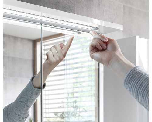 Detailaufnahme eines Spiegelschranks mit Hand, die einen Mechanismus berührt