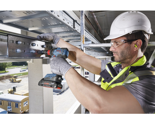 Ein Bauarbeiter befestigt mit einem Akku-Bohrschrauber eine Metallschiene.
