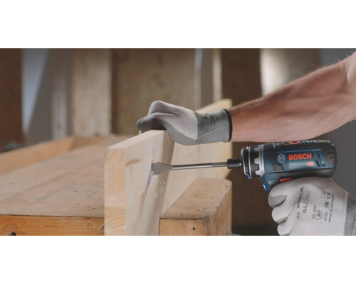 Eine Person bohrt mit einem Akku-Bohrschrauber ein Loch in ein Holzbrett.