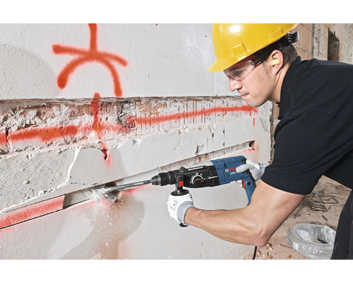 Ein Mann bohrt mit einem Bohrhammer ein Loch in eine Wand.