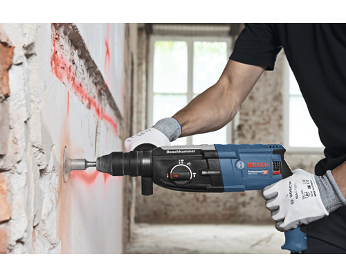 Ein Mann bohrt mit einem Bosch Bohrhammer ein Loch in eine Wand.