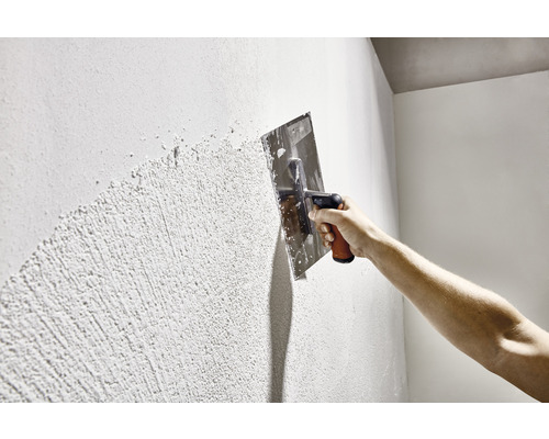 Auftragen von Putz mit einer Glättkelle auf eine Wand