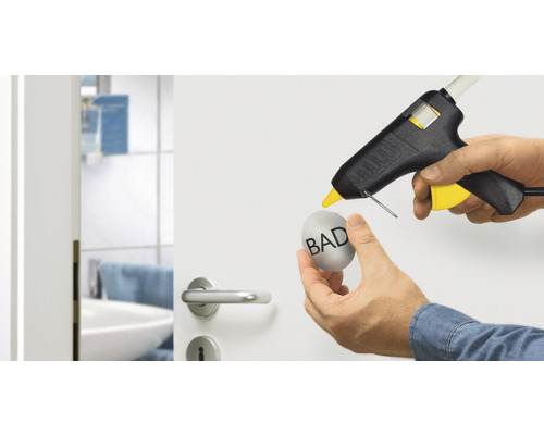 Heißklebepistole beim Anbringen eines Objekts an einer Tür