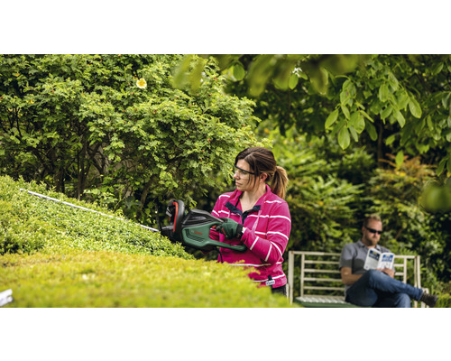 "Frau schneidet Hecke mit Heckenschere