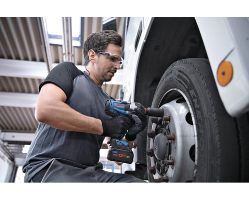 Ein Mann verwendet einen Akku-Drehschlagschrauber, um ein Rad an einem Fahrzeug zu befestigen.