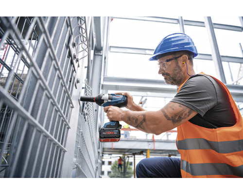 Ein Arbeiter benutzt einen Akku-Drehschlagschrauber an einer Metallkonstruktion.