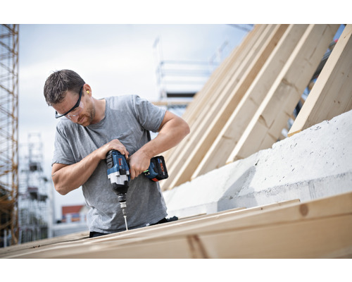 Ein Handwerker befestigt mit einem Akku-Bohrschrauber Schrauben an einem Holzrahmen.