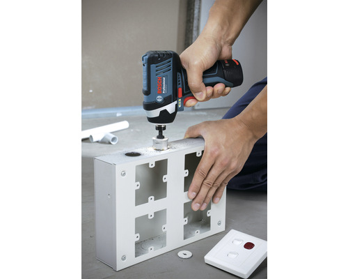 Eine Person bohrt mit einem Akku-Bohrschrauber ein Loch in ein Metallgehäuse.