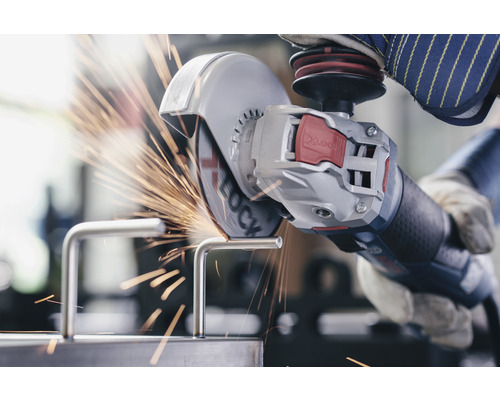 Eine Person benutzt einen Winkelschleifer zum Schneiden eines Metallstücks, wobei Funken entstehen.