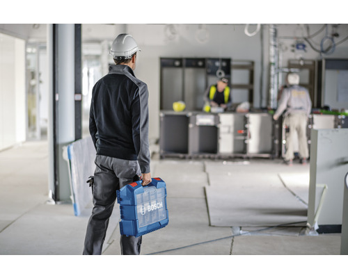 Ein Bauarbeiter mit einem Werkzeugkoffer der Marke Bosch auf einer Baustelle.