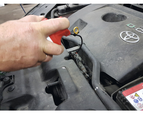 Motorraum eines Autos wird mit einem Reiniger gesäubert.