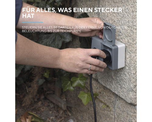 Person steckt Stecker in eine wetterfeste Außensteckdose