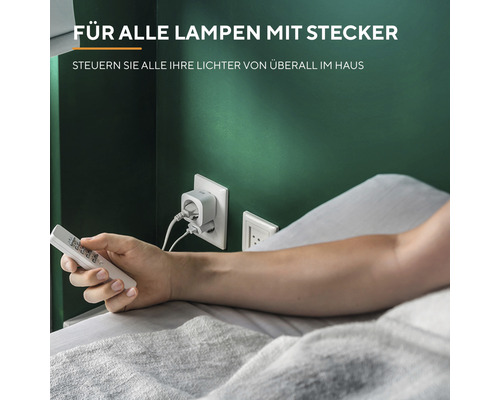 Person im Bett, die eine Lampe mit einem Smart Plug und einer Fernbedienung steuert.
