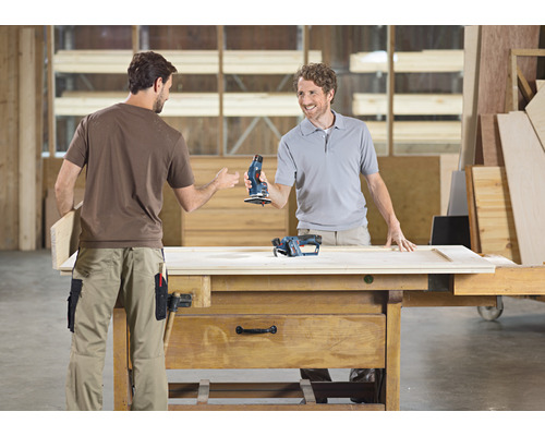 Zwei Männer an Werkbank mit Schleifgeräten in Werkstatt