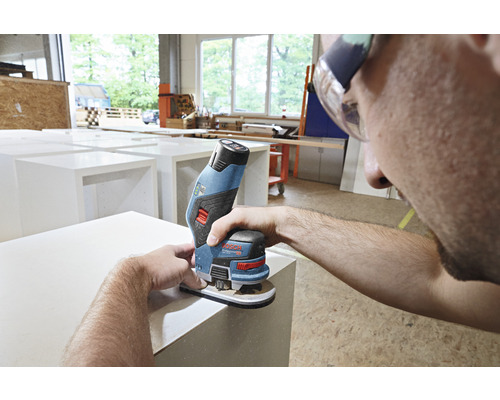 Ein Mann schleift mit einem Akku-Multischleifer eine Oberfläche.