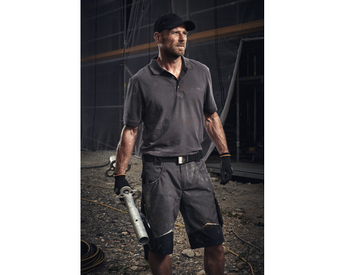 Mann in Arbeitskleidung mit Rohren auf einer Baustelle
