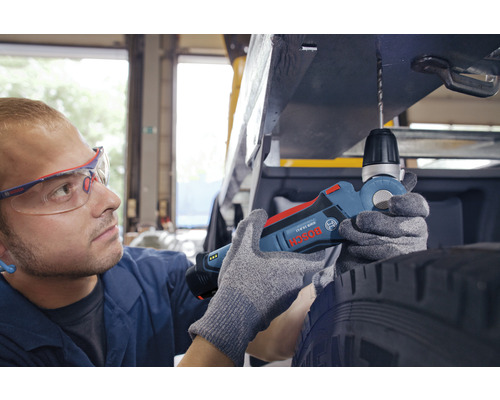 Ein Mann bohrt mit einer Bosch Winkelbohrmaschine ein Loch in ein Fahrzeug.