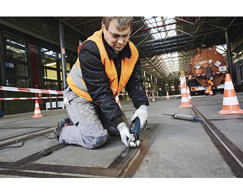Handwerker bei der Arbeit mit einem Multifunktionswerkzeug in einer Werkshalle