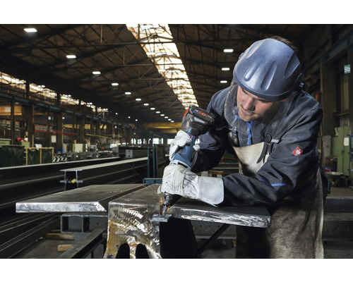 Metallarbeiter mit Akku-Blechknabber im Werkstattbereich beim Bearbeiten von Metall