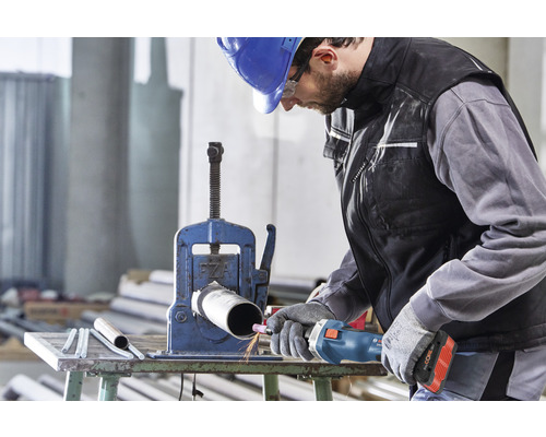 Handwerker bearbeitet ein Rohr mit einem Rohrschneider in einer Werkstatt.