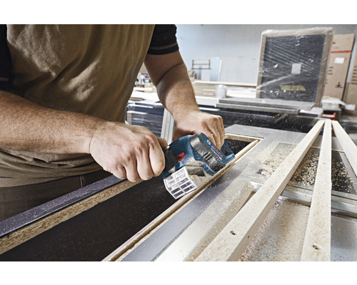 Eine Person verwendet eine Akku-Tauchsäge von Bosch zum Schneiden eines Holzstücks.