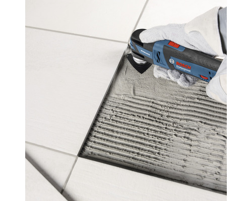 Fliesenschneider im Einsatz zum Entfernen von Fugenmasse zwischen Fliesen.