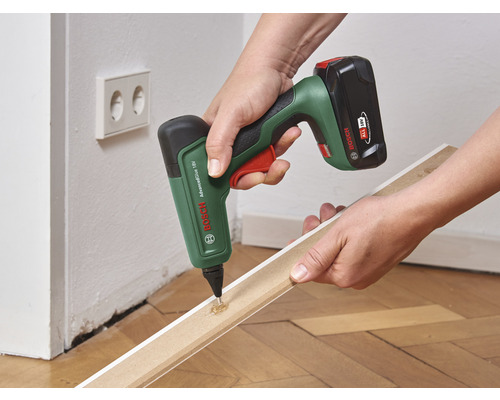 Akkuklebestift beim Auftragen von Klebstoff auf eine Holzleiste