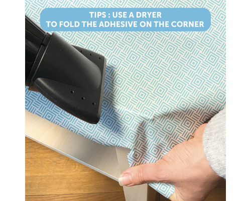 Aufbringen einer selbstklebenden Folie mit einem Haartrockner auf eine Tischkante