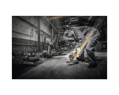 Ein Mann in Schutzkleidung schneidet Metall mit einem Winkelschleifer in einer Werkstatt, wobei Funken entstehen.