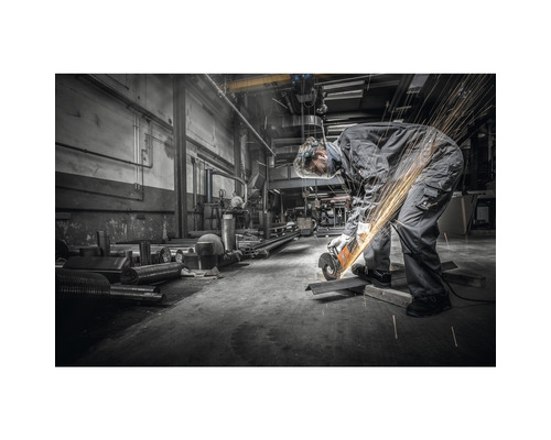 Ein Arbeiter mit einer Flex bearbeitet Metall in einer Werkstatt.