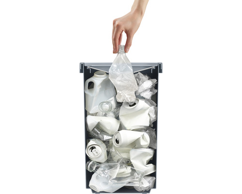 Hand wirft Plastikflasche in Wertstofftonne mit anderem Recyclingmaterial