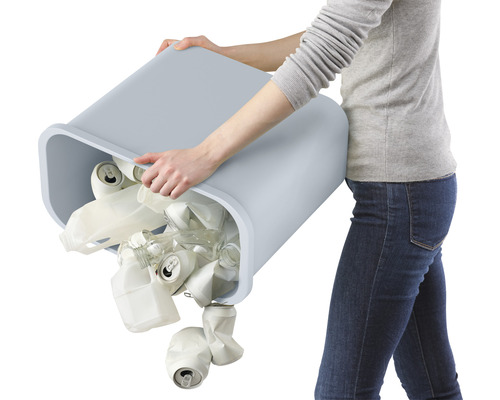 Frau leert Mülleimer mit Dosen und Plastikflaschen aus