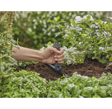 Eine Person verwendet ein Montagewerkzeug zur Installation eines Tropfers in einem Gartenbewässerungssystem.