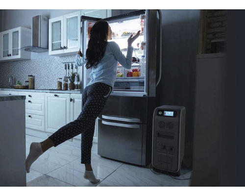 Frau steht vor einem Kühlschrank neben einem Stromgenerator in einer Küche.