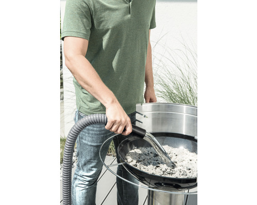 Mann saugt Asche aus einem Grill mit einem Aschesauger