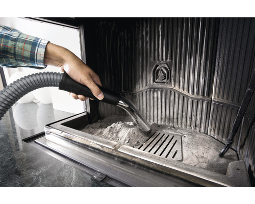 Person saugt Asche aus einem Kamin mit einem Aschesauger