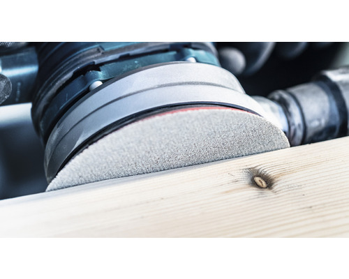 Nahaufnahme eines Exzenterschleifers beim Schleifen eines Holzstücks.