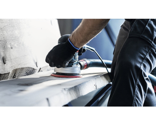 Eine Person schleift Holz mit einem elektrischen Exzenterschleifer.